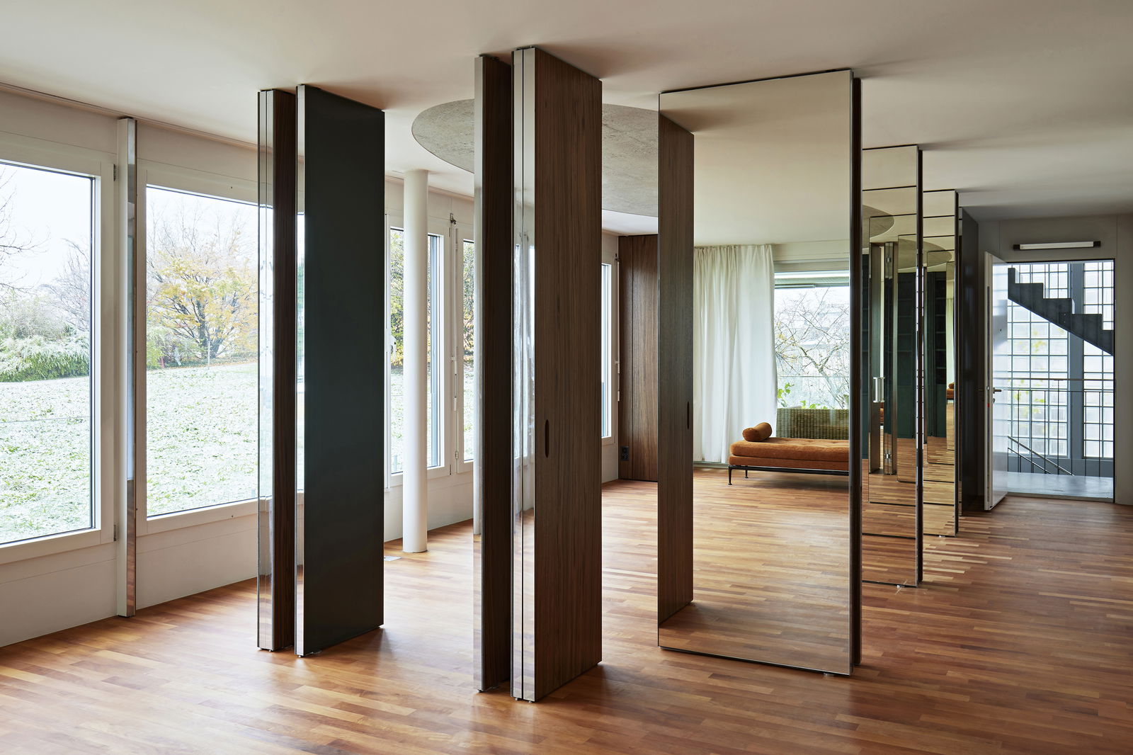 A series of 10 adaptable pivot doors combining walnut, mirrors, and bold green panels.