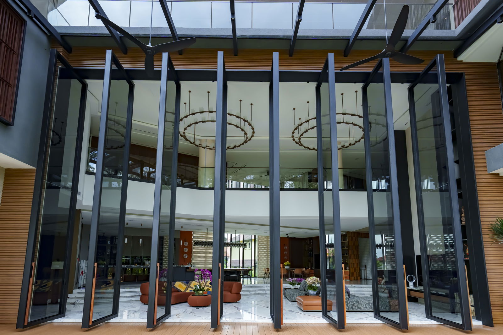 A monumental 7-meter-tall pivot door with sleek black aluminum framing and expansive glass panels.