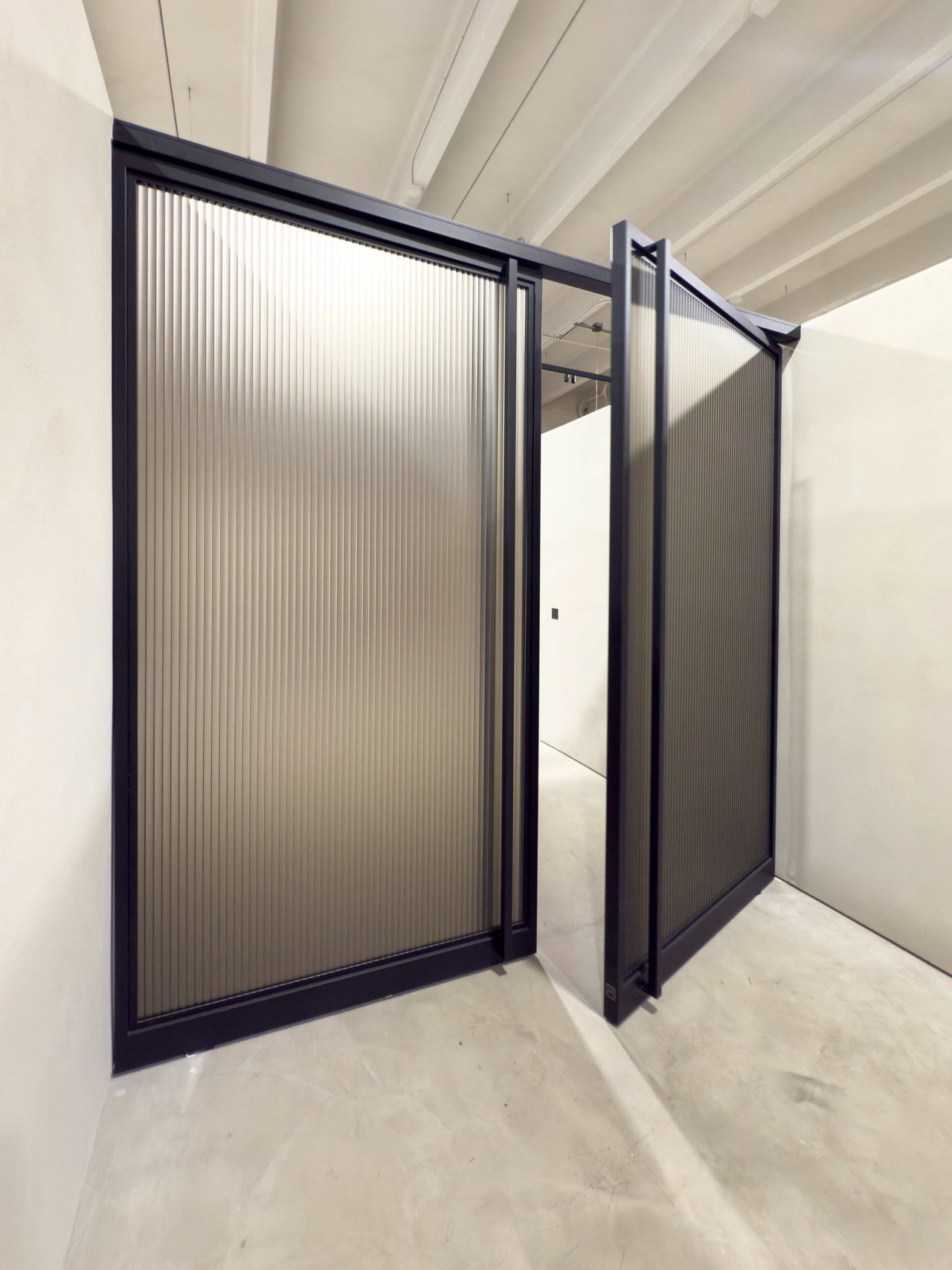Steel and glass pivot door in a showroom in Miami with FritsJurgens System M+ pivot hinge system inside
