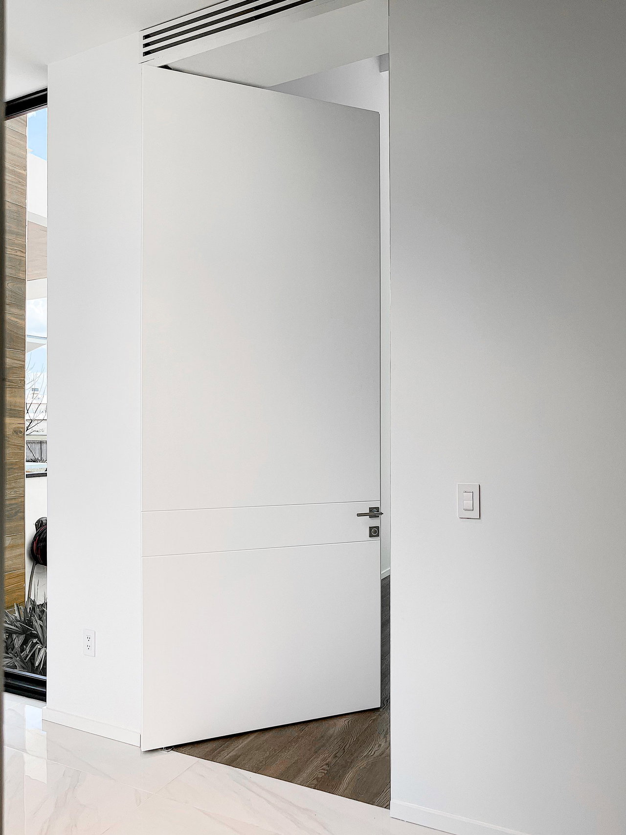 Wooden pivot door in a private home in Weston with FritsJurgens System One pivot hinge system inside