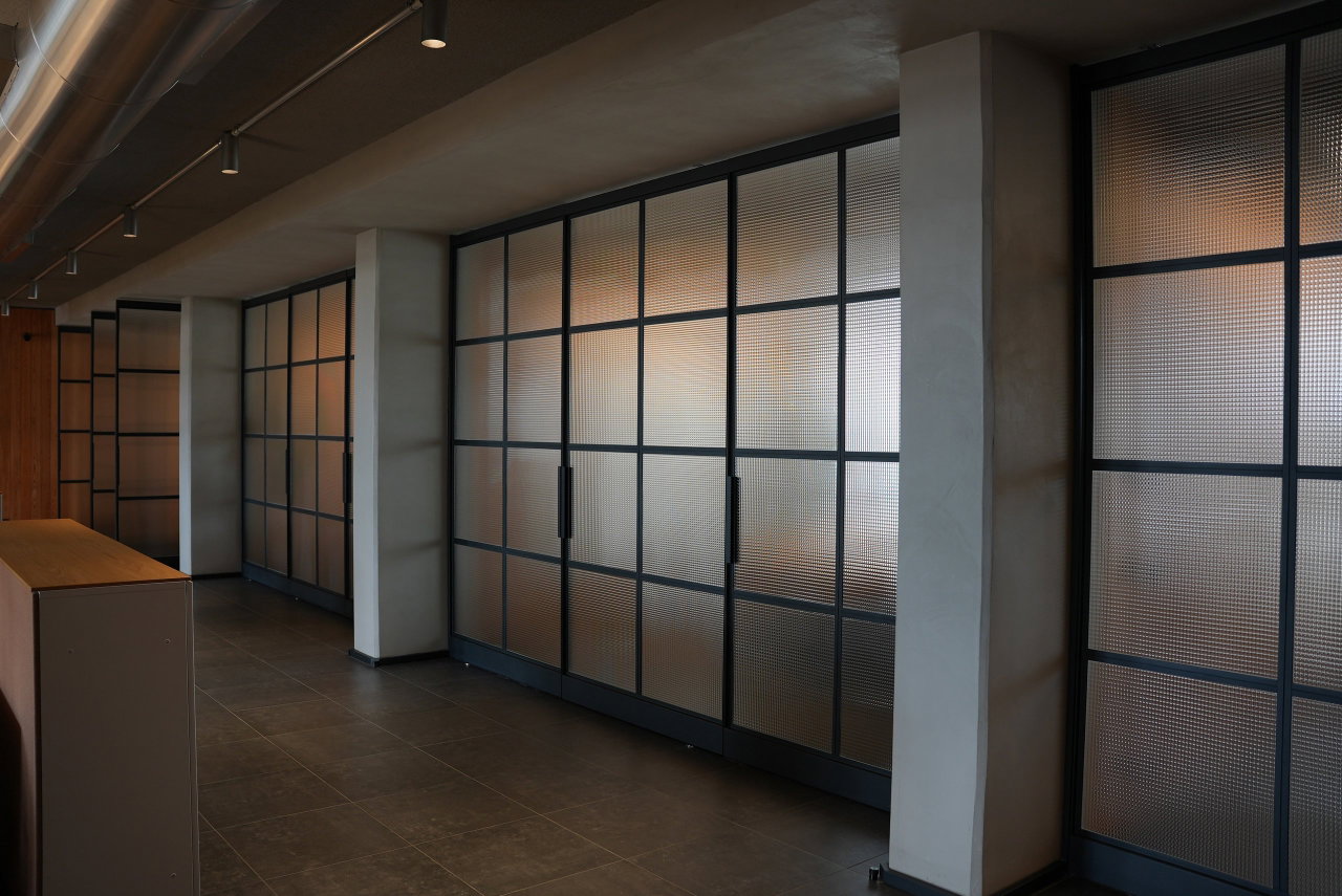 Puerta pivotante de acero y vidrio en una oficina en Lisboa con bisagra pivotante FritsJurgens System M+ en el interior