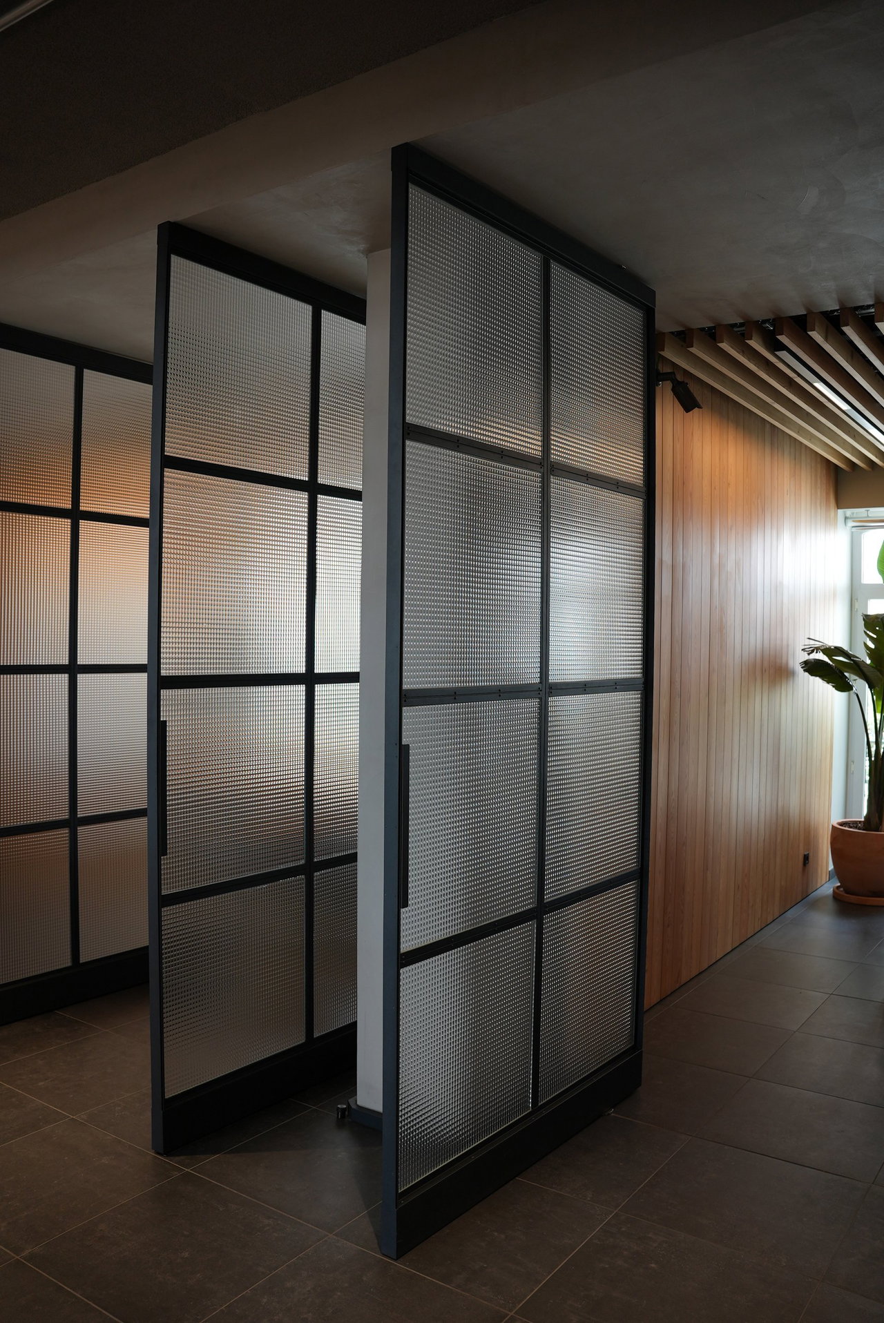 Puerta pivotante de acero y vidrio en una oficina en Lisboa con bisagra pivotante FritsJurgens System M+ en el interior