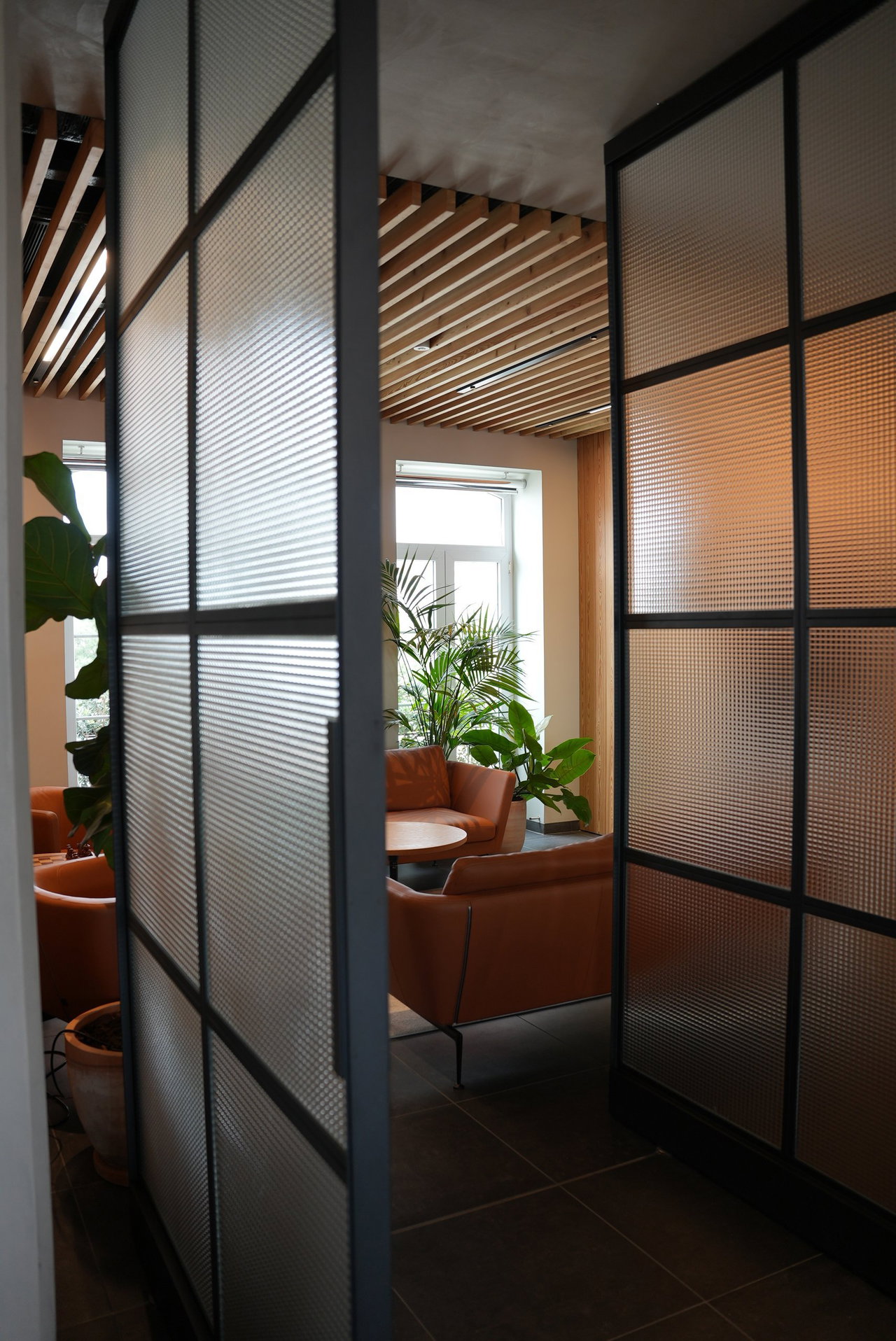Puerta pivotante de acero y vidrio en una oficina en Lisboa con bisagra pivotante FritsJurgens System M+ en el interior