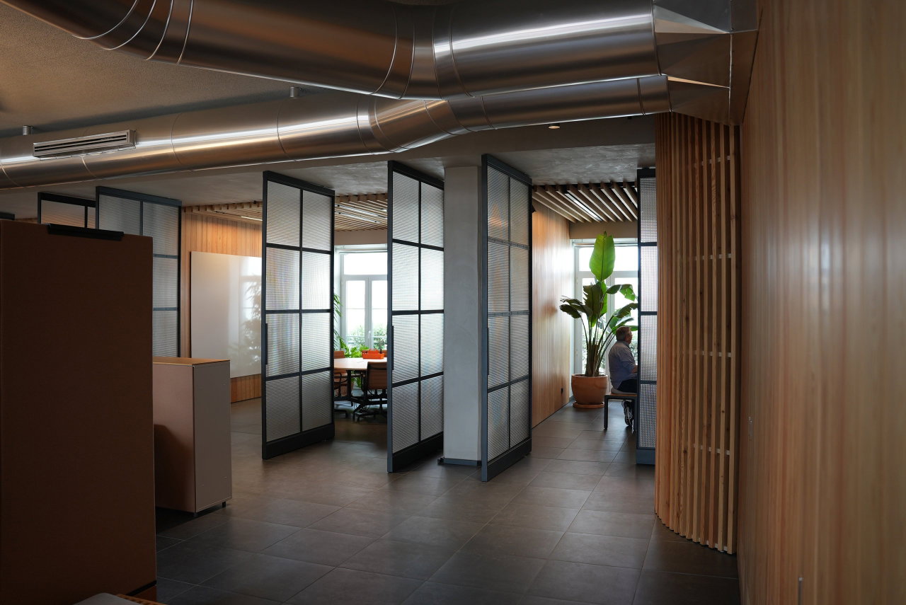 Puerta pivotante de acero y vidrio en una oficina en Lisboa con bisagra pivotante FritsJurgens System M+ en el interior