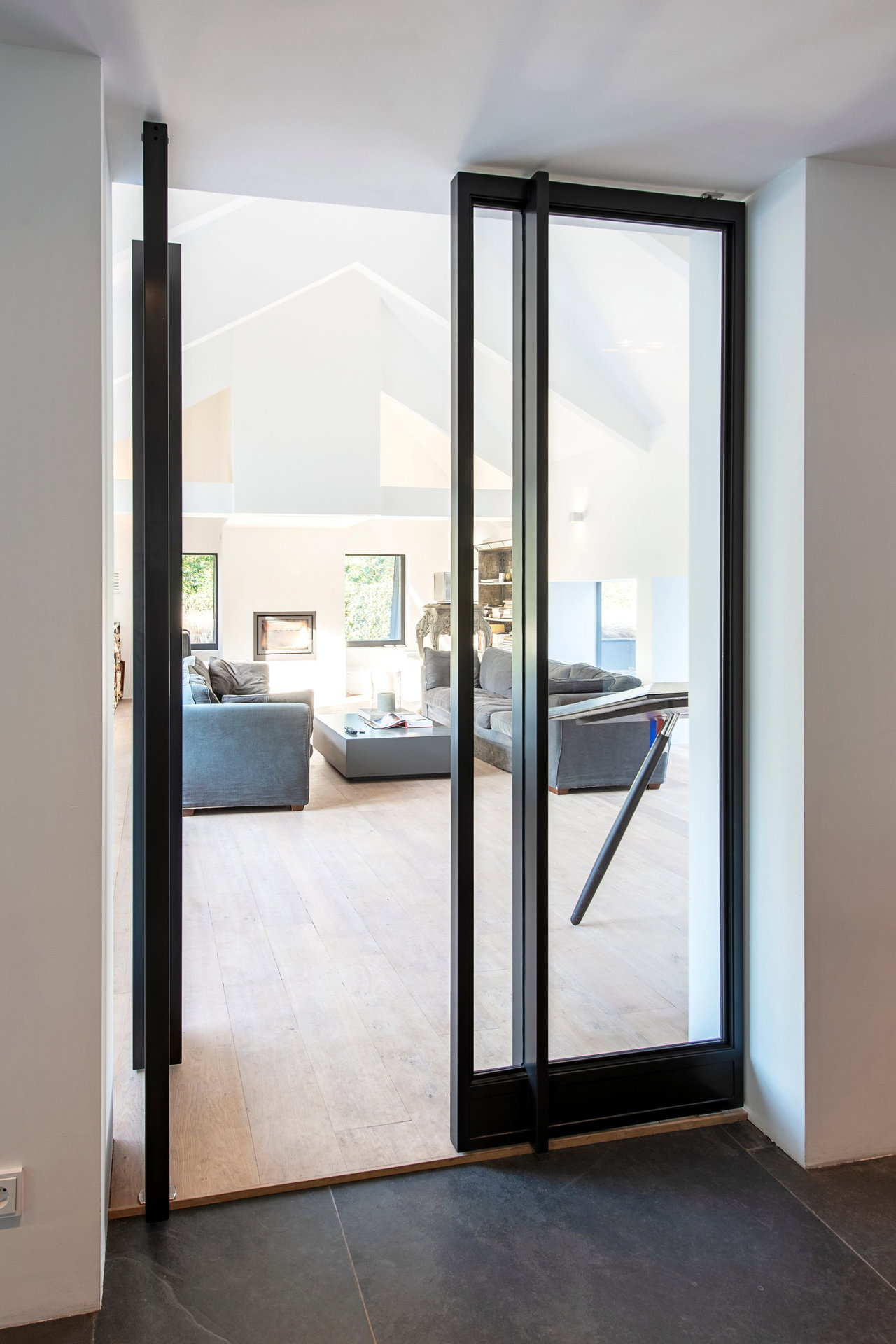 Steel and glass pivot door in a private home with FritsJurgens System M+ pivot hinge system inside