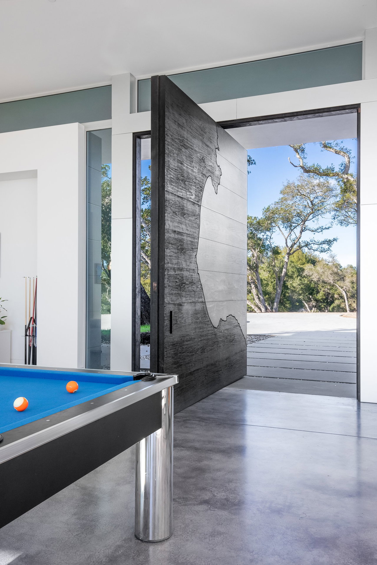 Wooden pivot door in a private home in Santa Cruz with FritsJurgens System M pivot hinge system inside